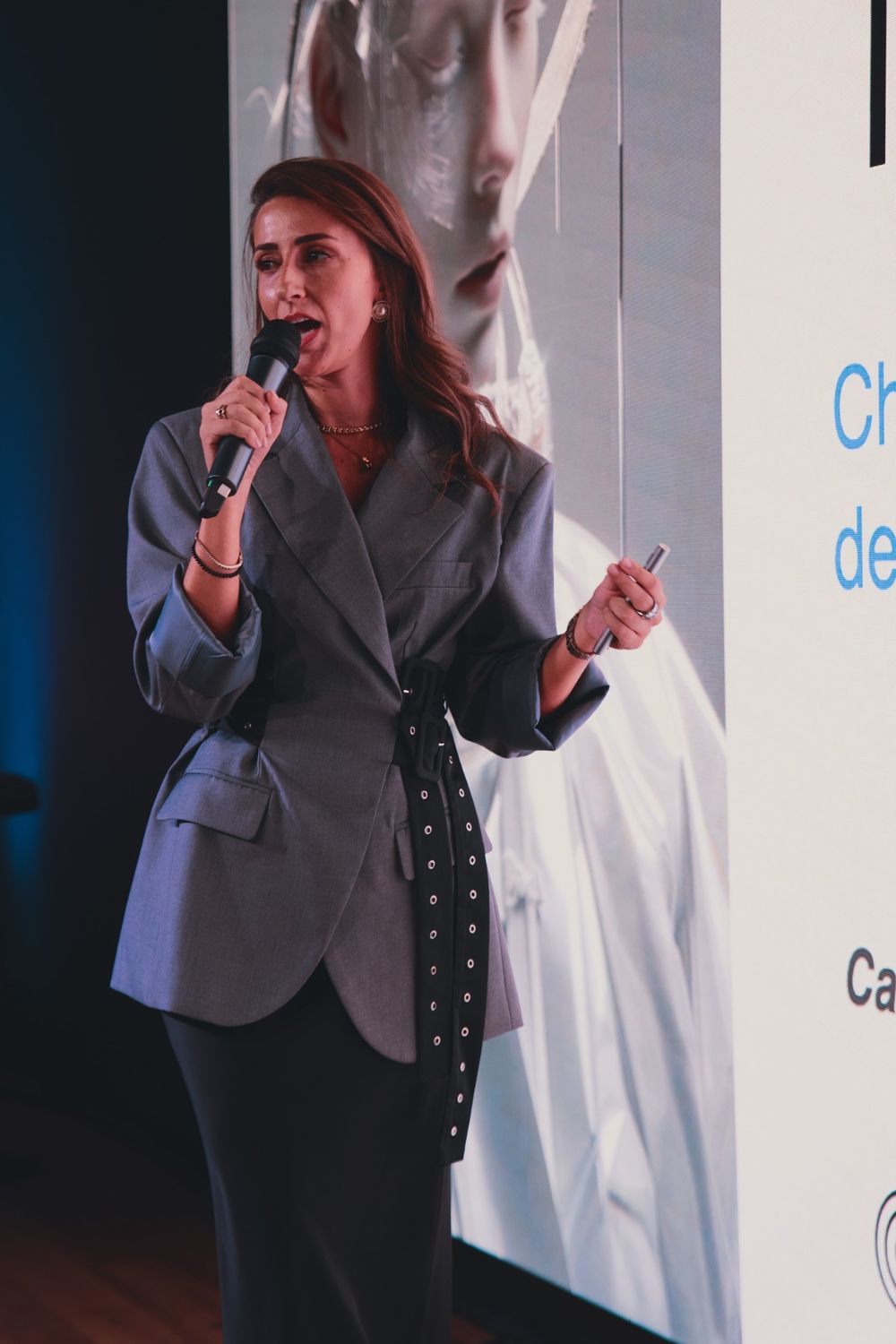 Camilla Brossa parla al microfono davanti a una slide, con il telecomando della presentazione in mano